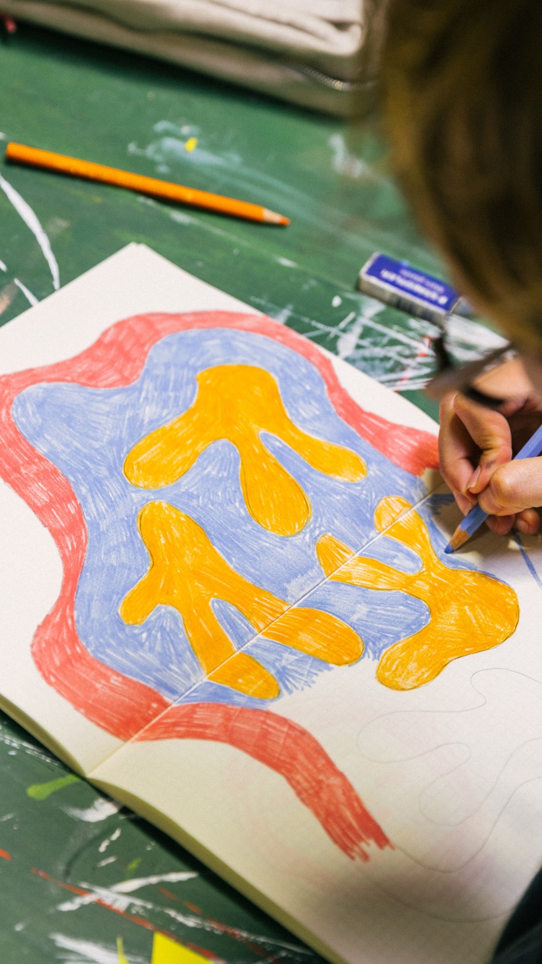 Close on Abbey Rich's hand shading a yellow and blue shape inside a red border