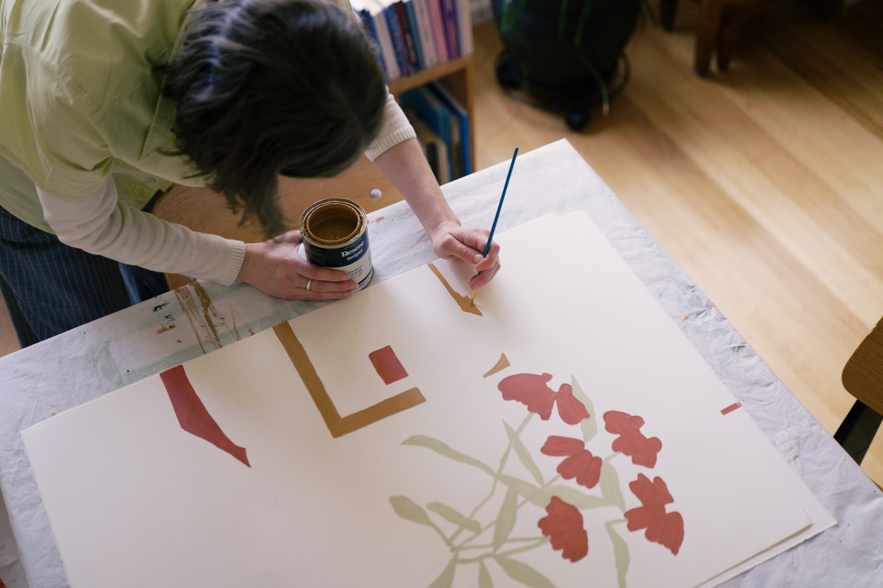 Looking down on the painting: red flowers, pale green leaves and blocks of orange