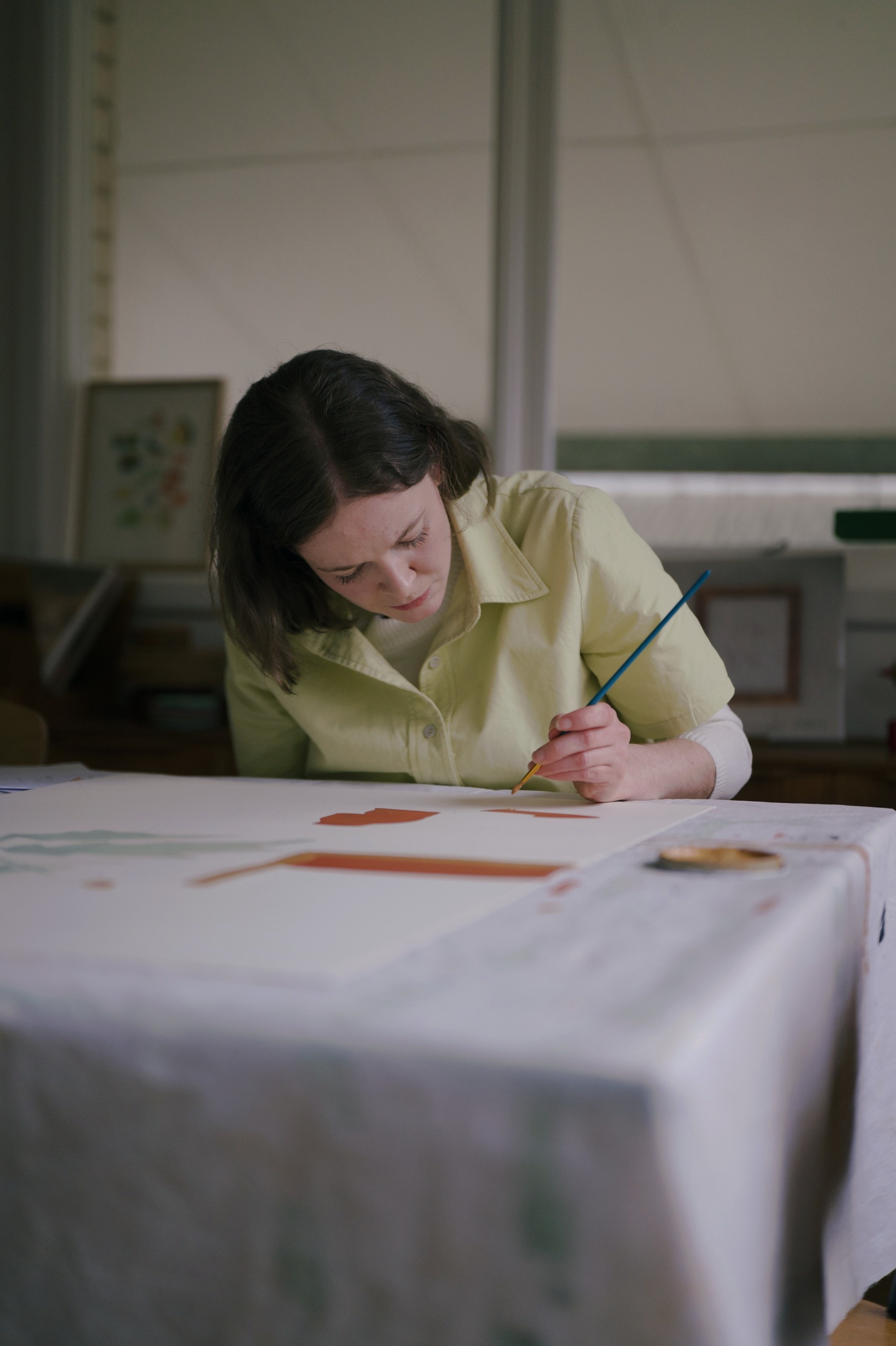Angharad Neal-Williams painting a fine line with a long brush at her table