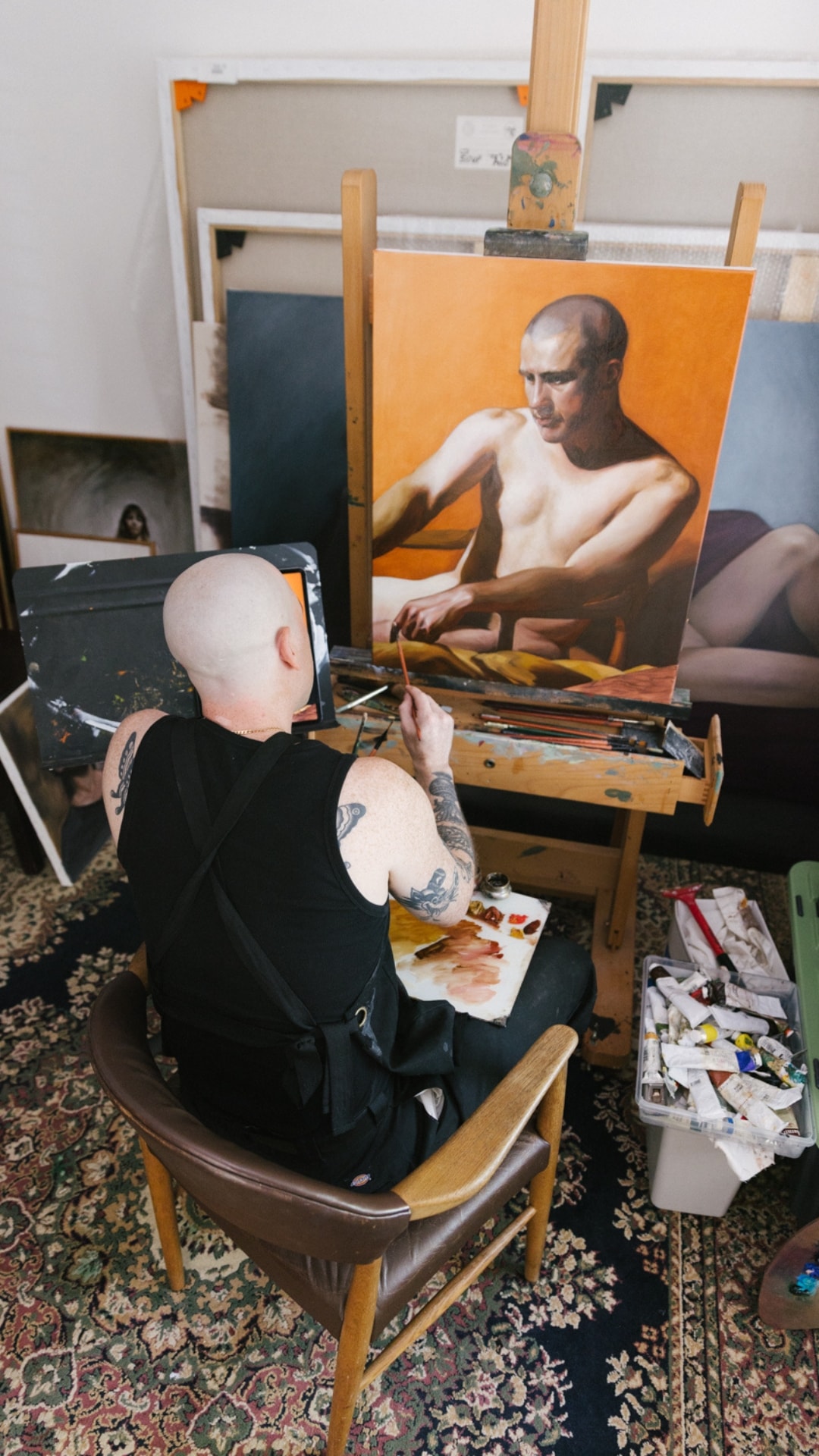 Anthony seated in a leather chair at his easel, palette on his knee