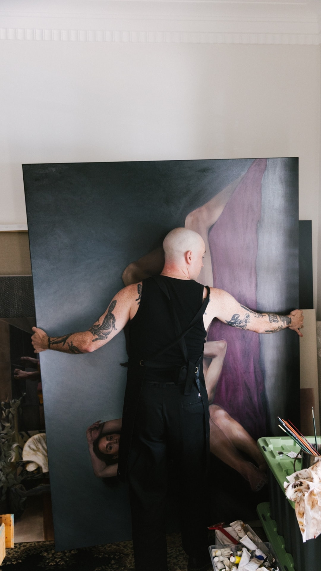 Anthony steadying a large canvas against the wall of his studio