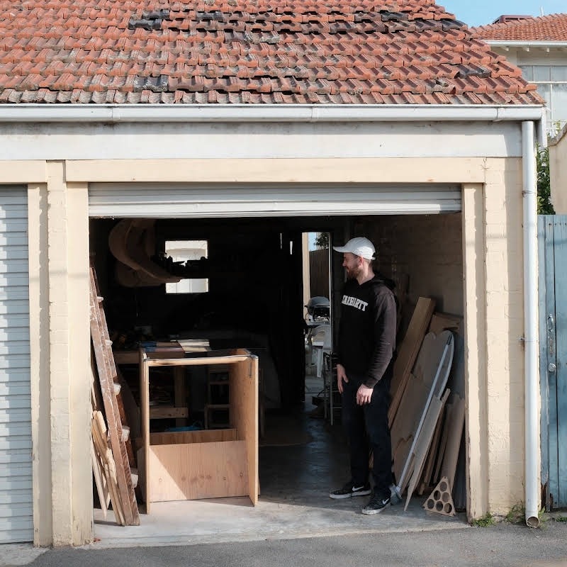 Billy Hietanen standing in the open door of his garage workshop, timber stacked inside