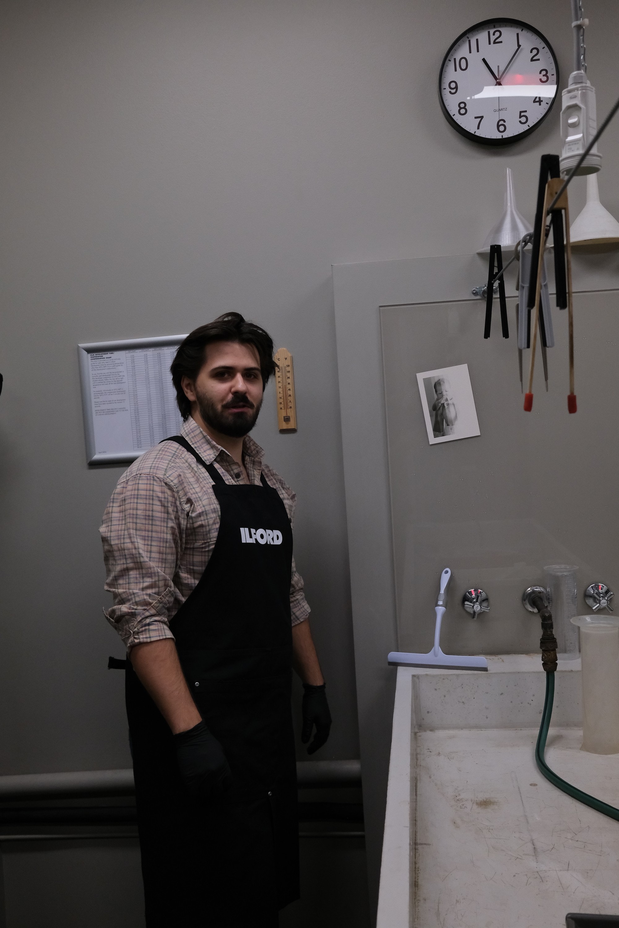 Dillon Jevon standing by the darkroom sink in his gloves and apron