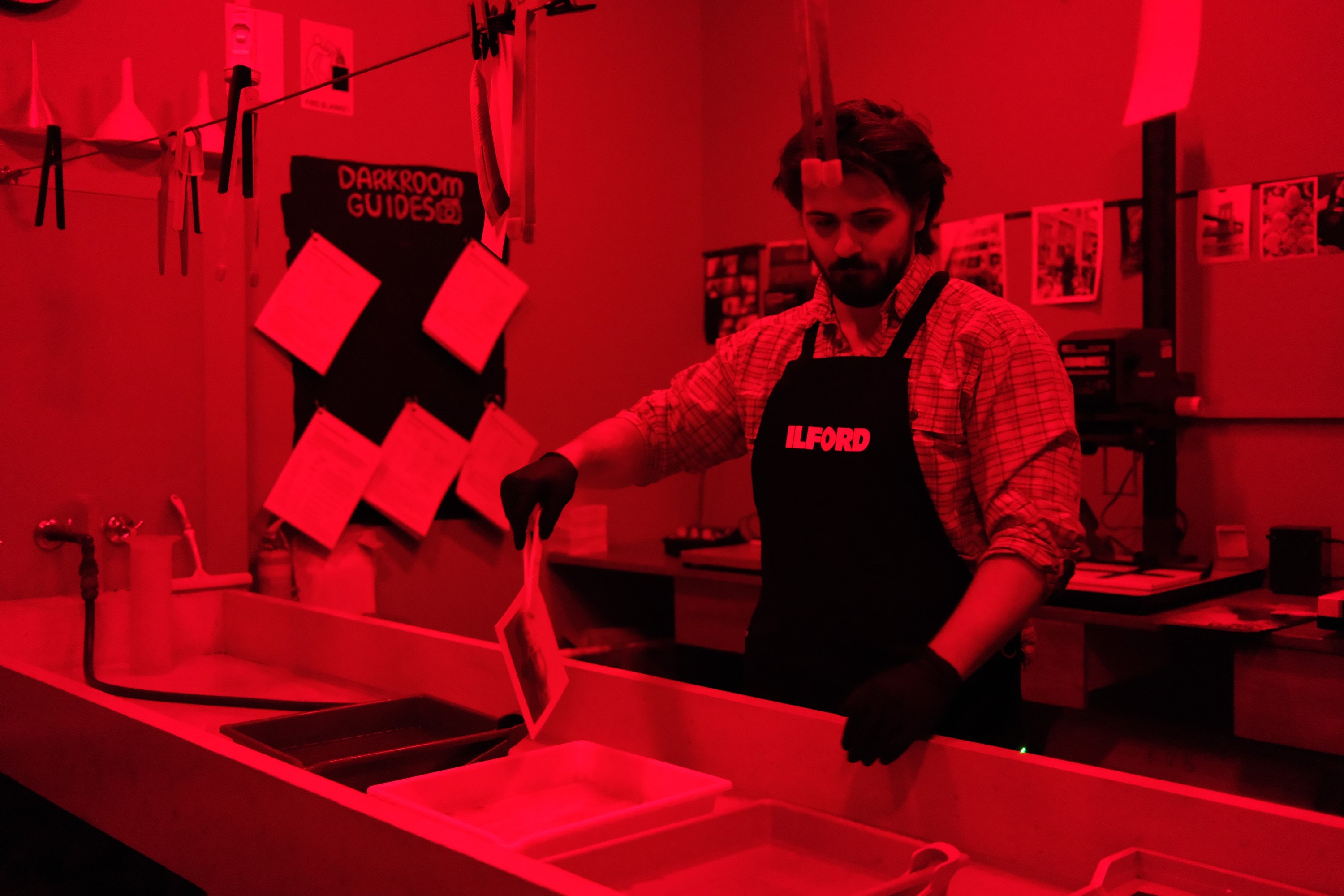 Dillon lifting a print out of the final tray under the red safelight