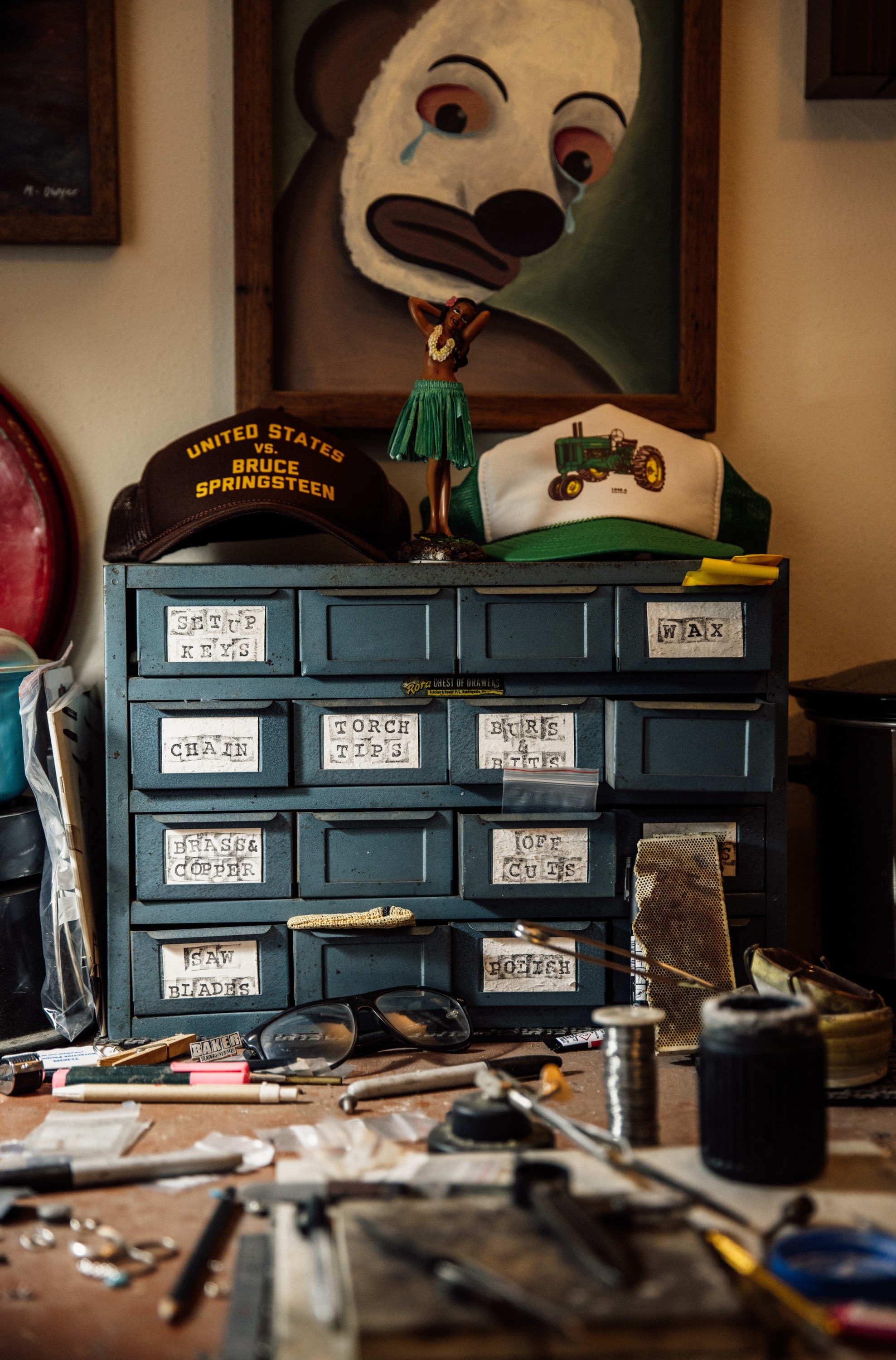 A set of labelled drawers on the bench, caps hung on the wall above