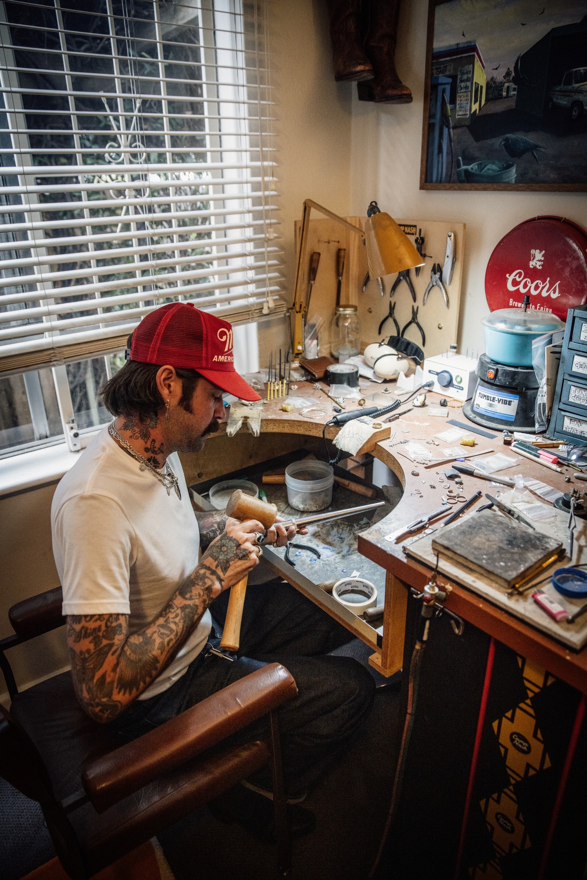 Adam at his bench by the window, a lamp and tools around him