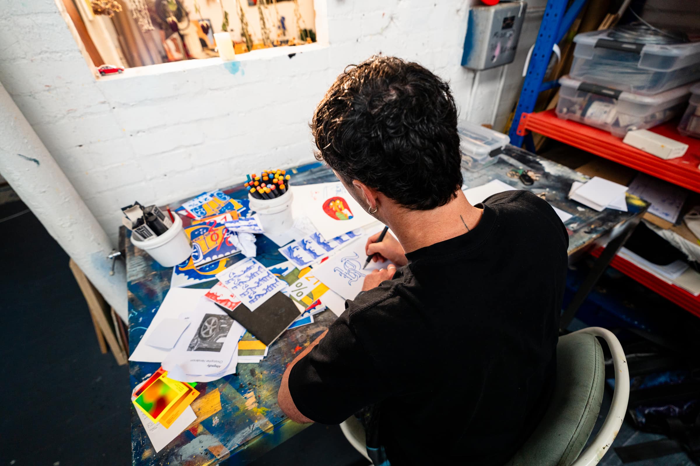Chris bent over a drawing at his studio desk