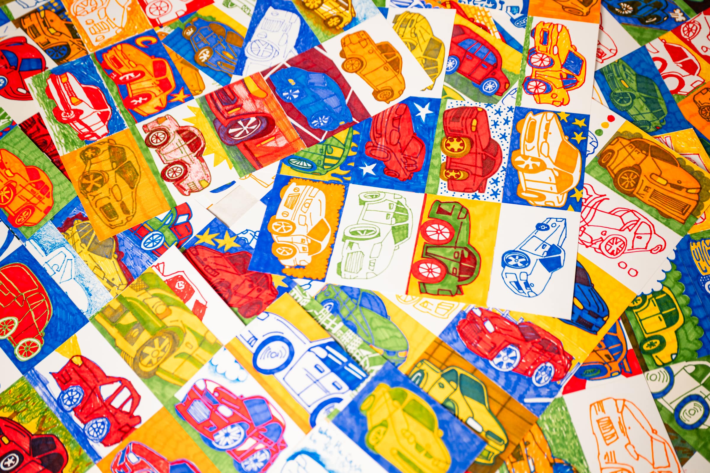 Hundreds of Commodore drawings in red, blue, yellow and green laid edge to edge, Chris’s hand on one of them