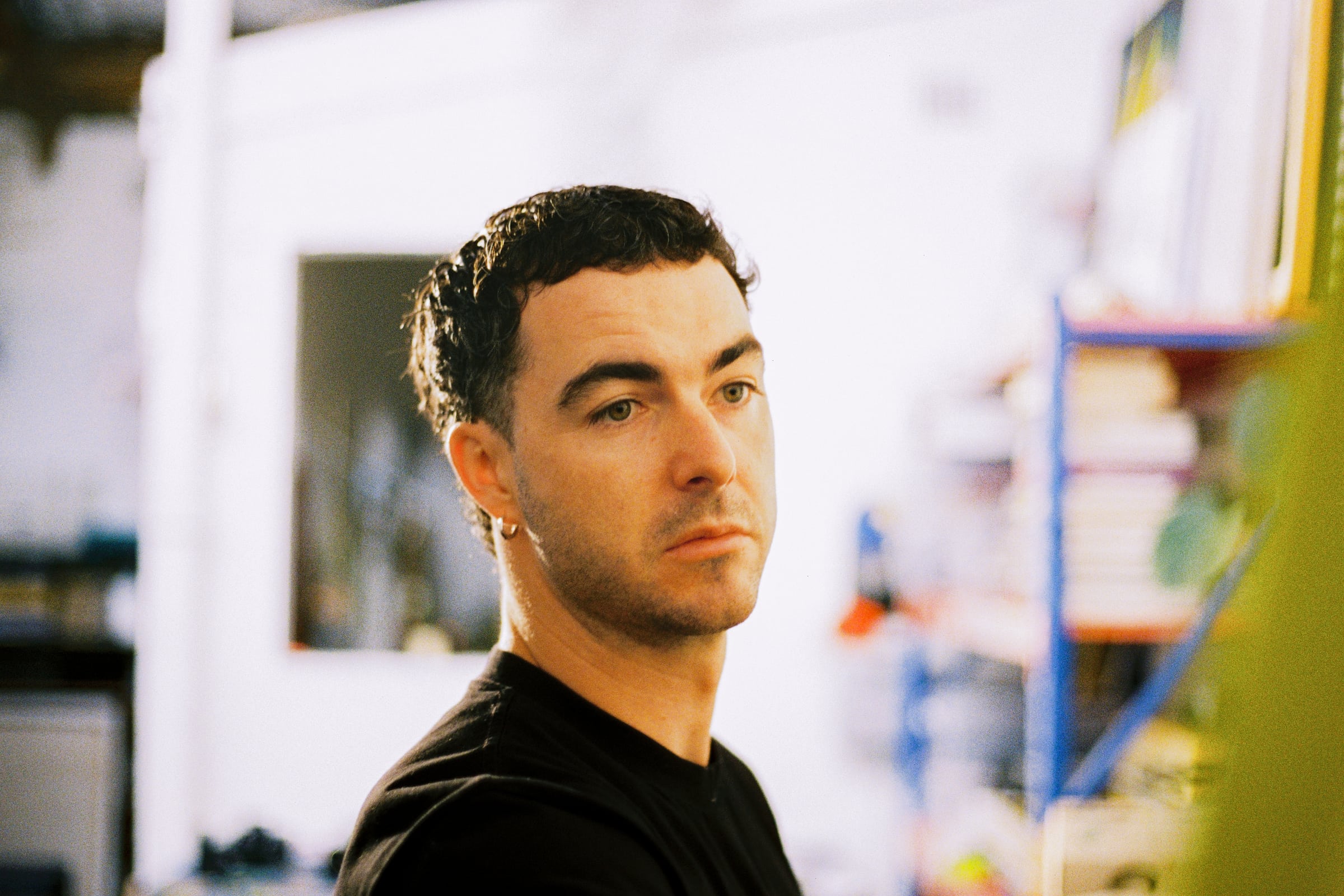 Chris in a black t-shirt, looking off to the side in his studio