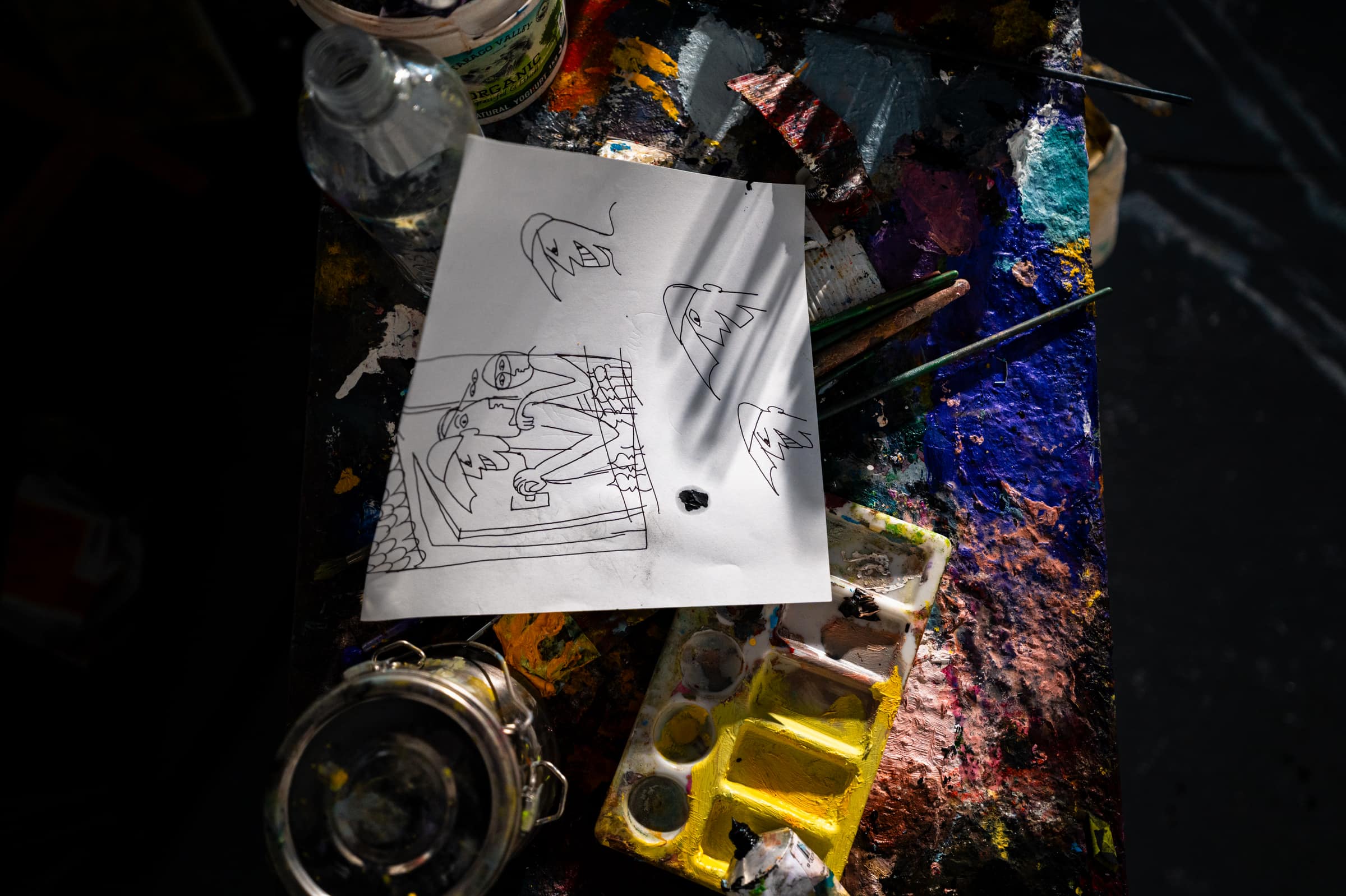 A pencil sketch of a car on paper, resting on a cluttered studio bench