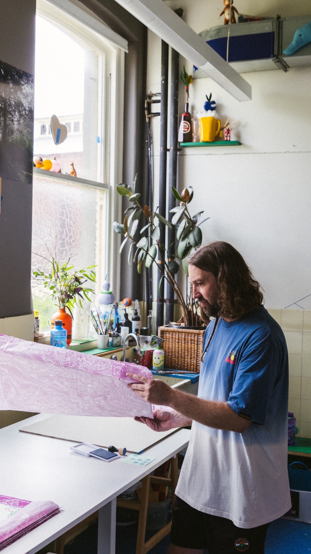 David Booth holding up a pink print by the studio window