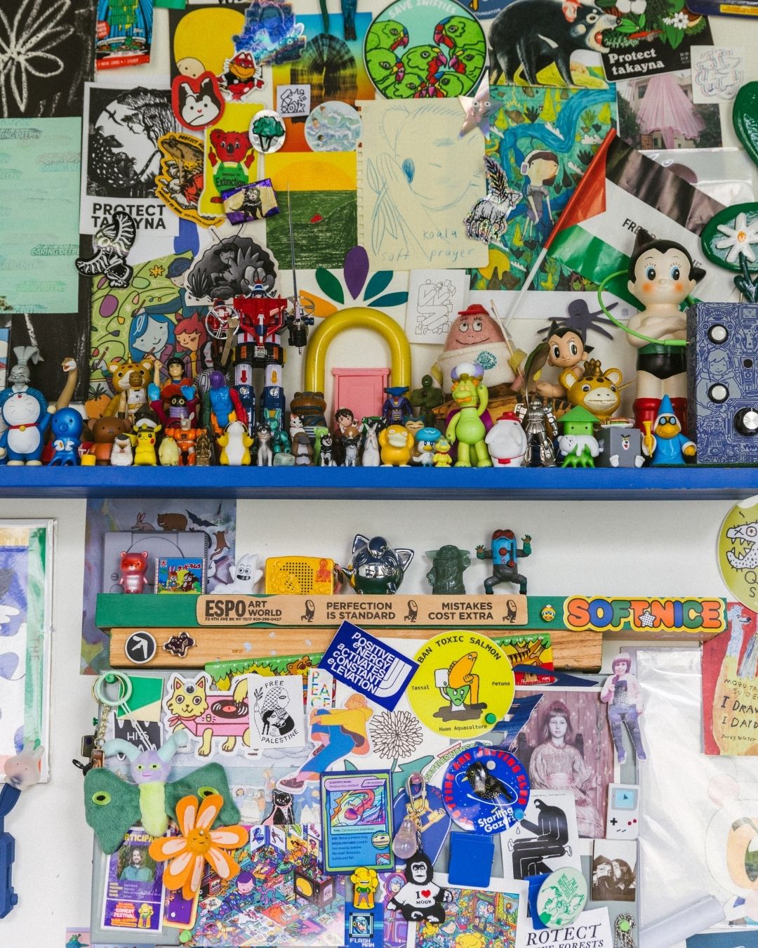 A wall in David Booth's studio crowded with toys, stickers, figurines and pinned drawings