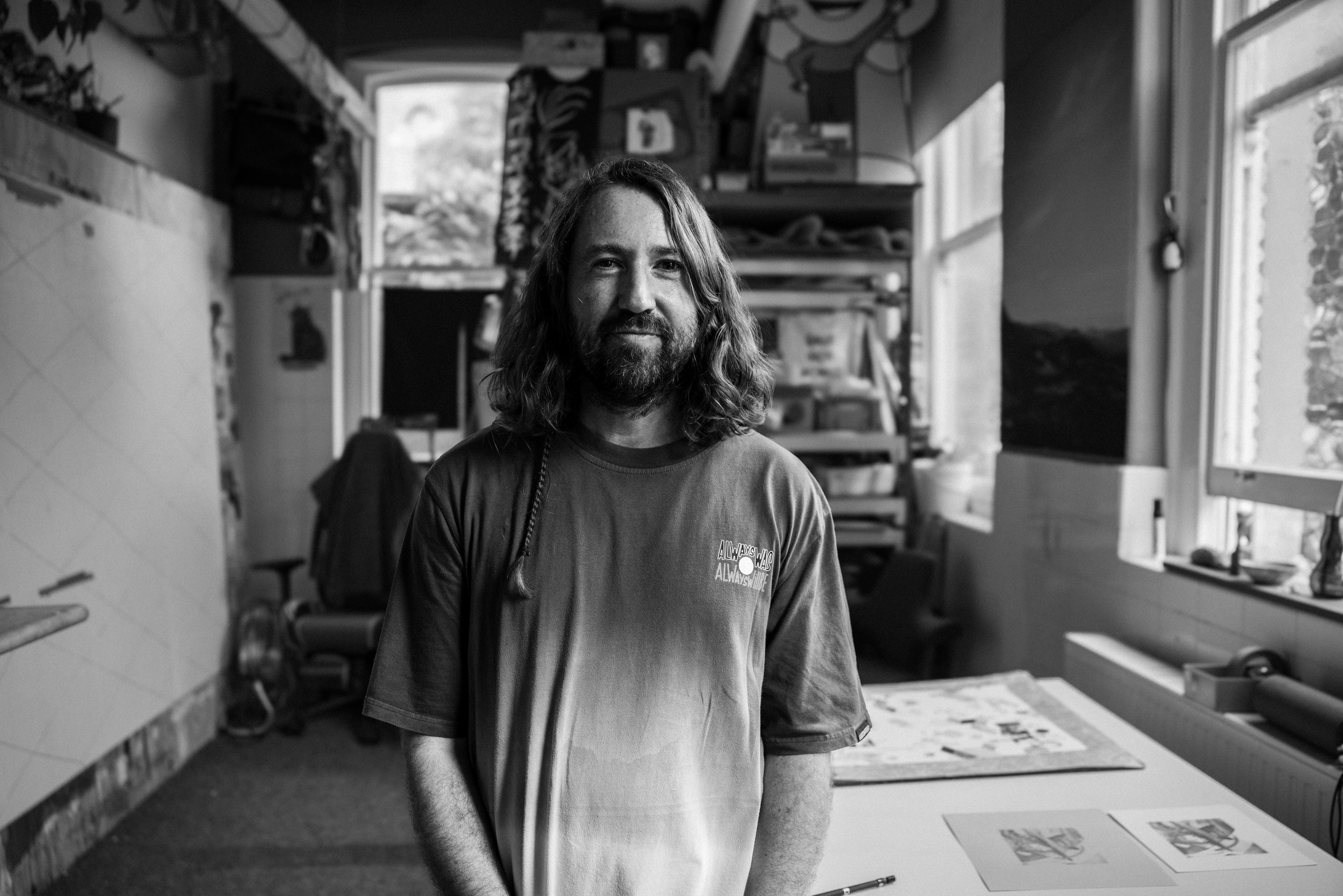 Black and white portrait of David Booth standing in his studio