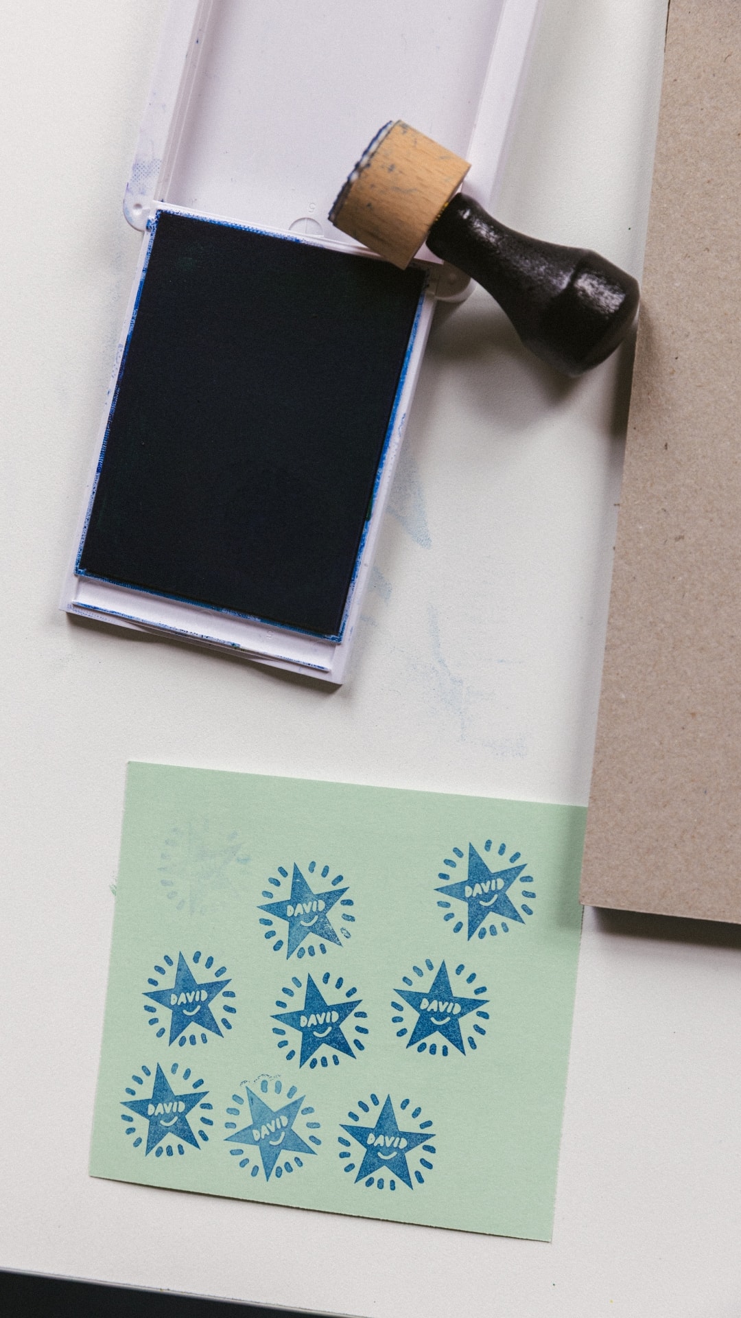 A rubber stamp and ink pad beside a sheet of blue star prints
