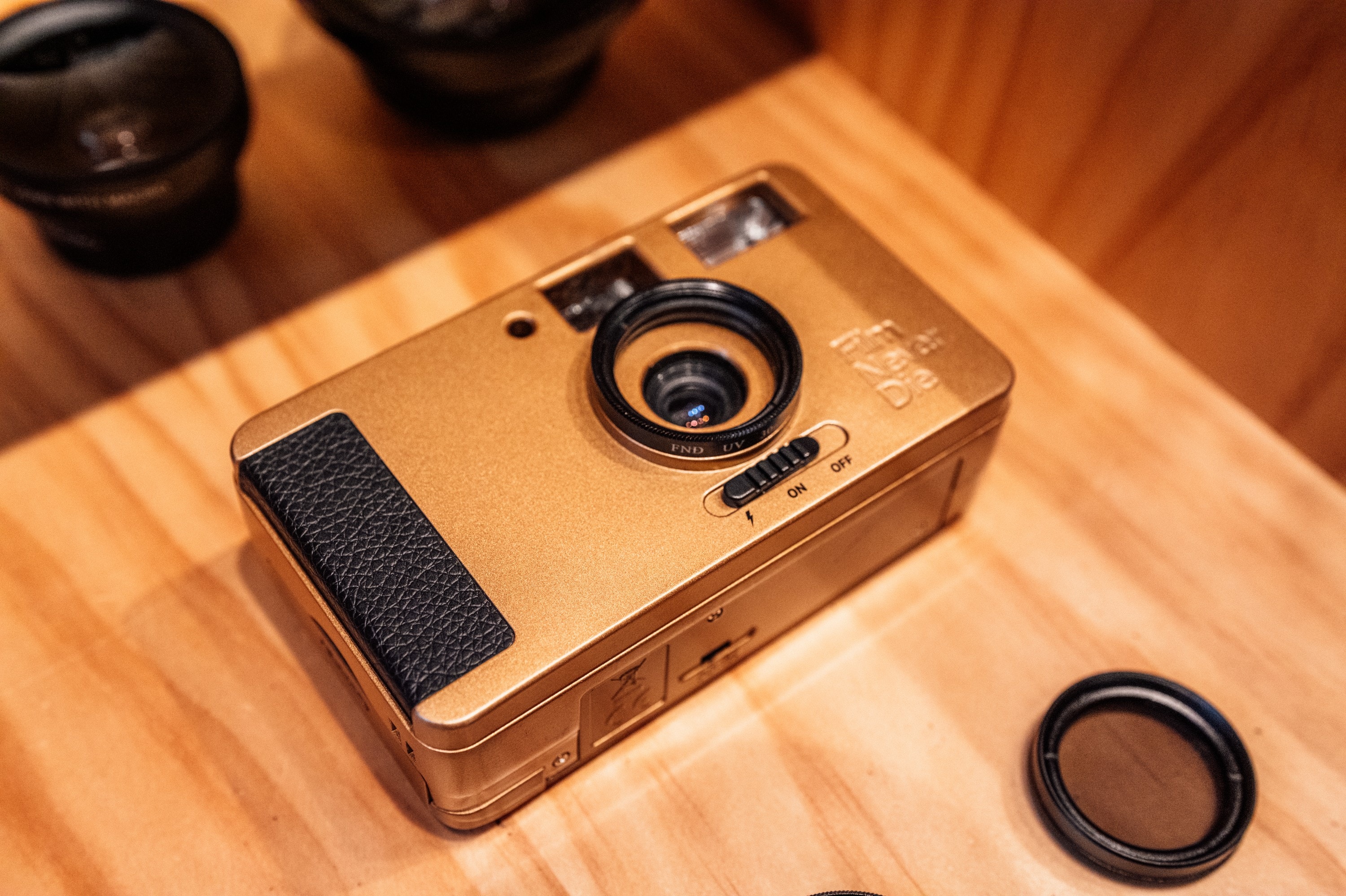 The gold Nana film camera on a wooden table