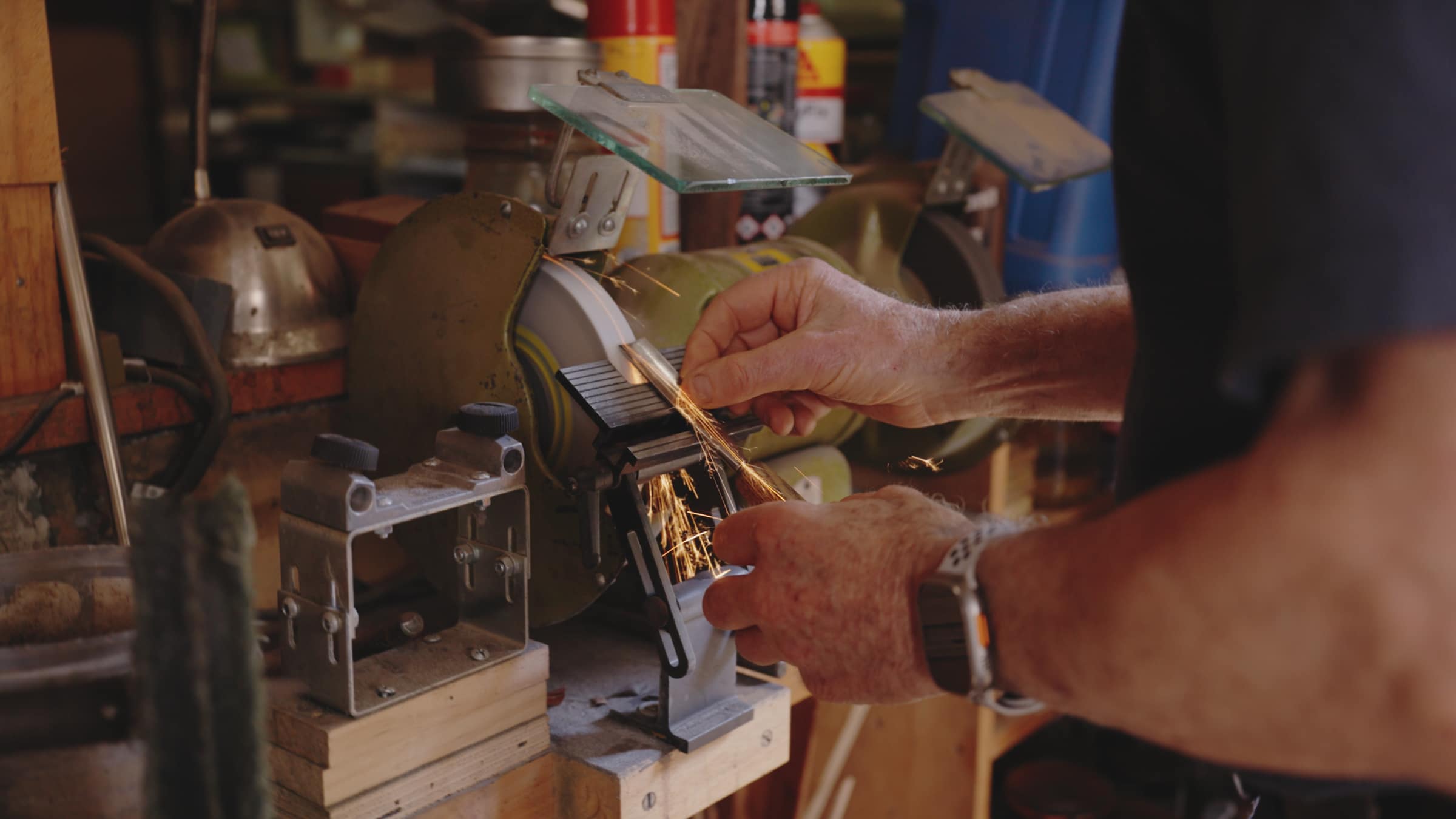 Robert sharpening a chisel on the grinder, sparks flying