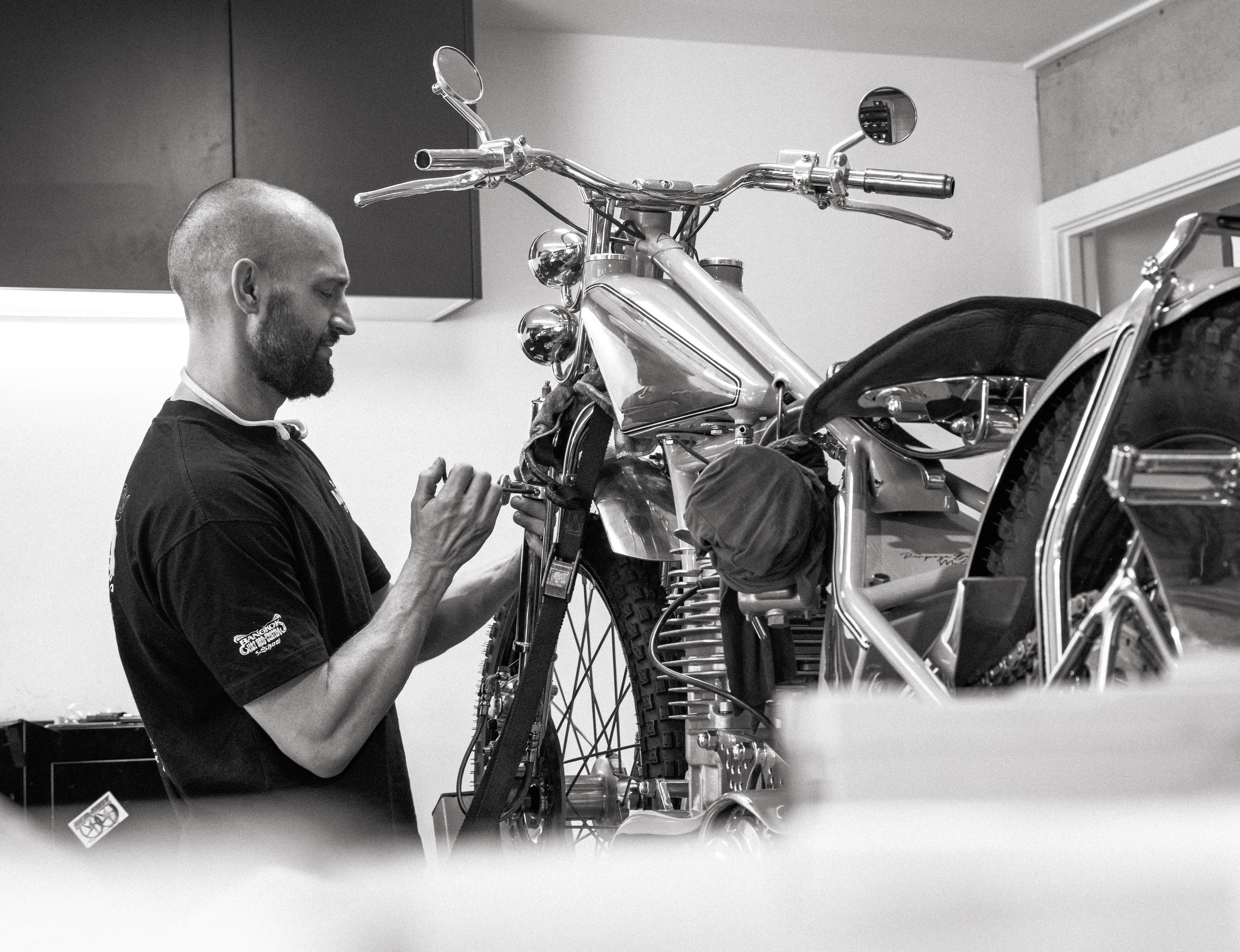 Tom Gilroy working on the front end of a custom motorcycle, in black and white
