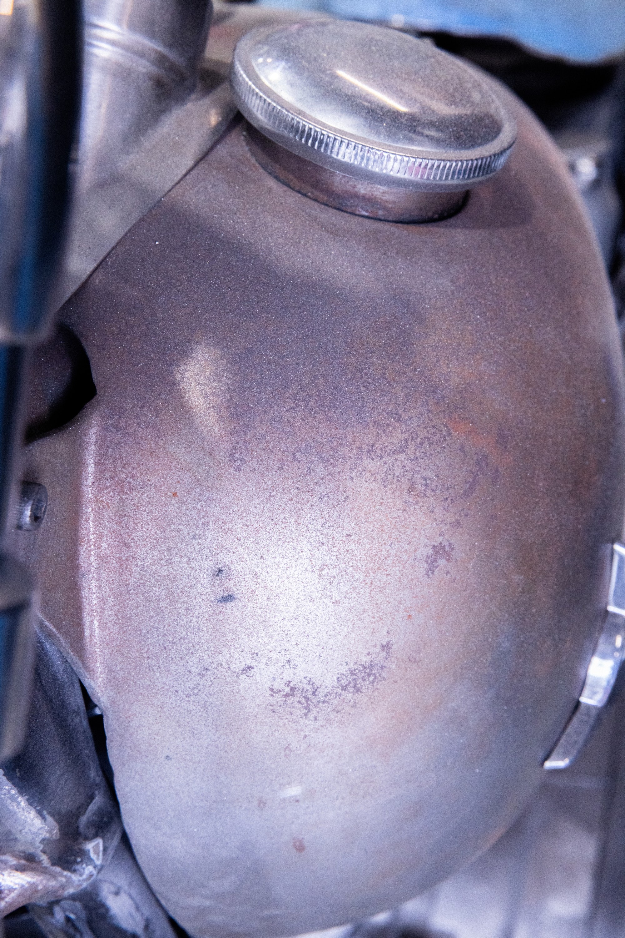 A bare metal fuel tank with its cap, close up