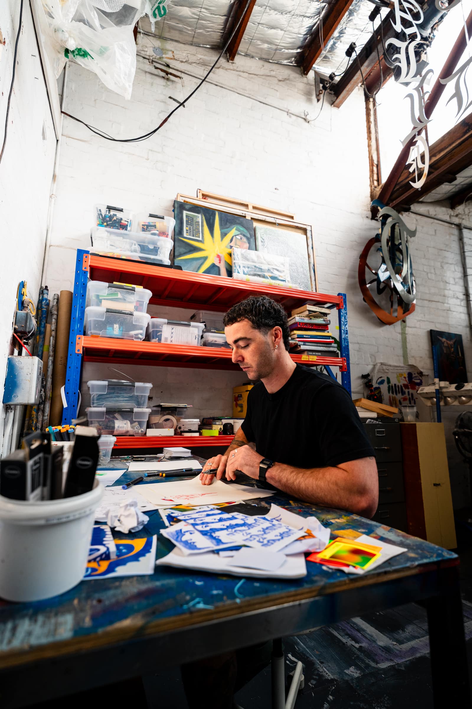 Chris drawing at his desk under the studio shelves