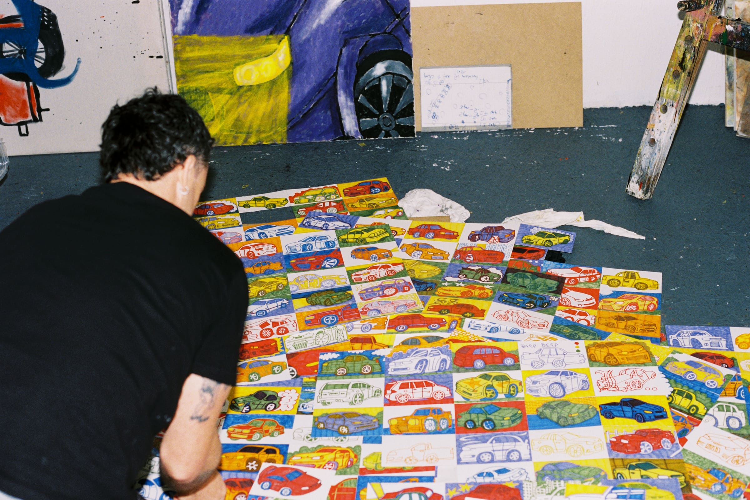 Chris leaning over the drawings spread across the studio floor, shot on film