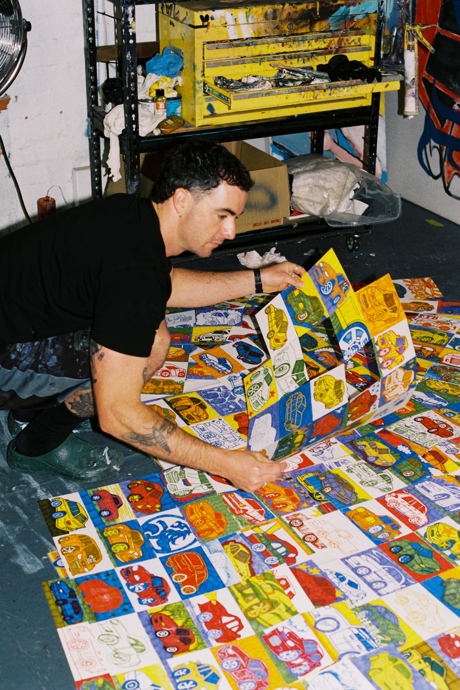 Chris kneeling over rows of Commodore drawings on the floor