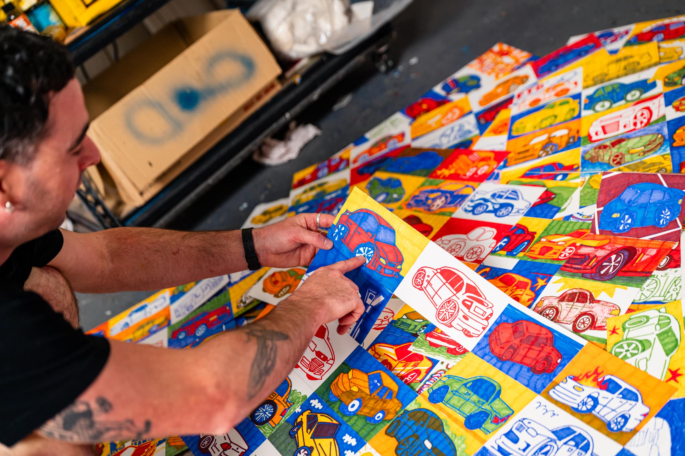 Chris pointing to the first Commodore he drew, among the others laid out on the studio floor