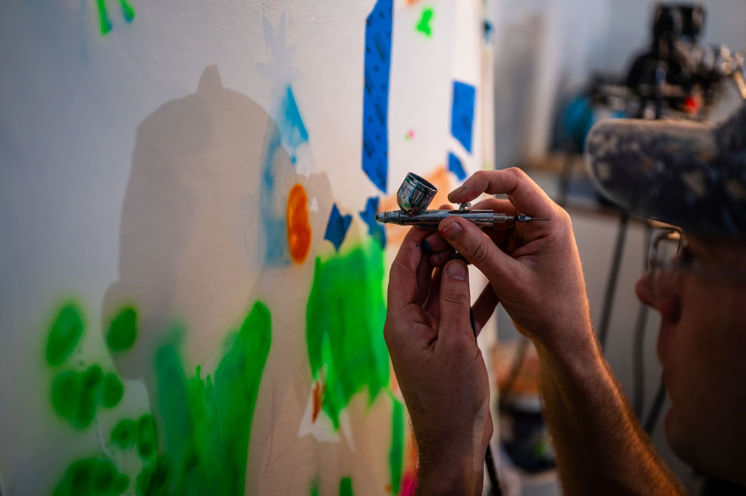 Close up of Liam's hands on the airbrush, spraying fluoro green
