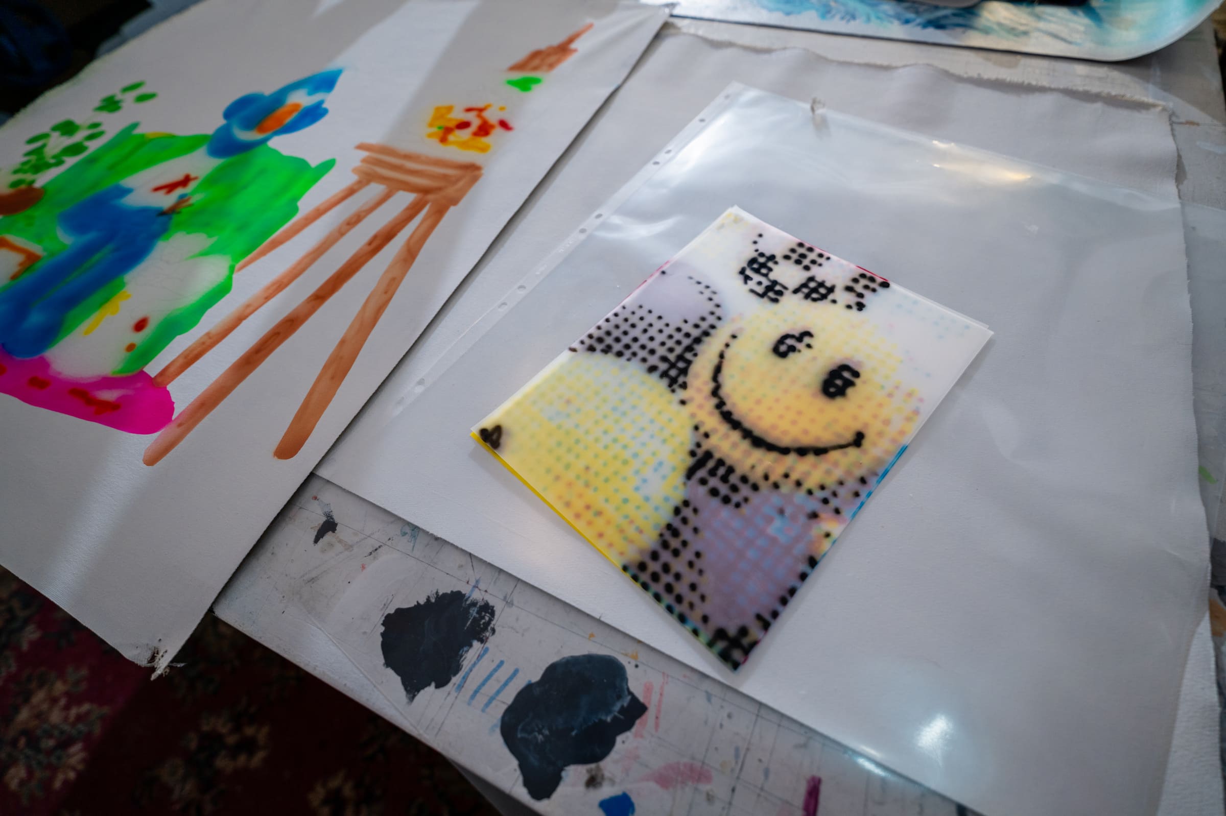 A halftone smiley face in yellow and black dots, lying on a sheet of plastic on the work table
