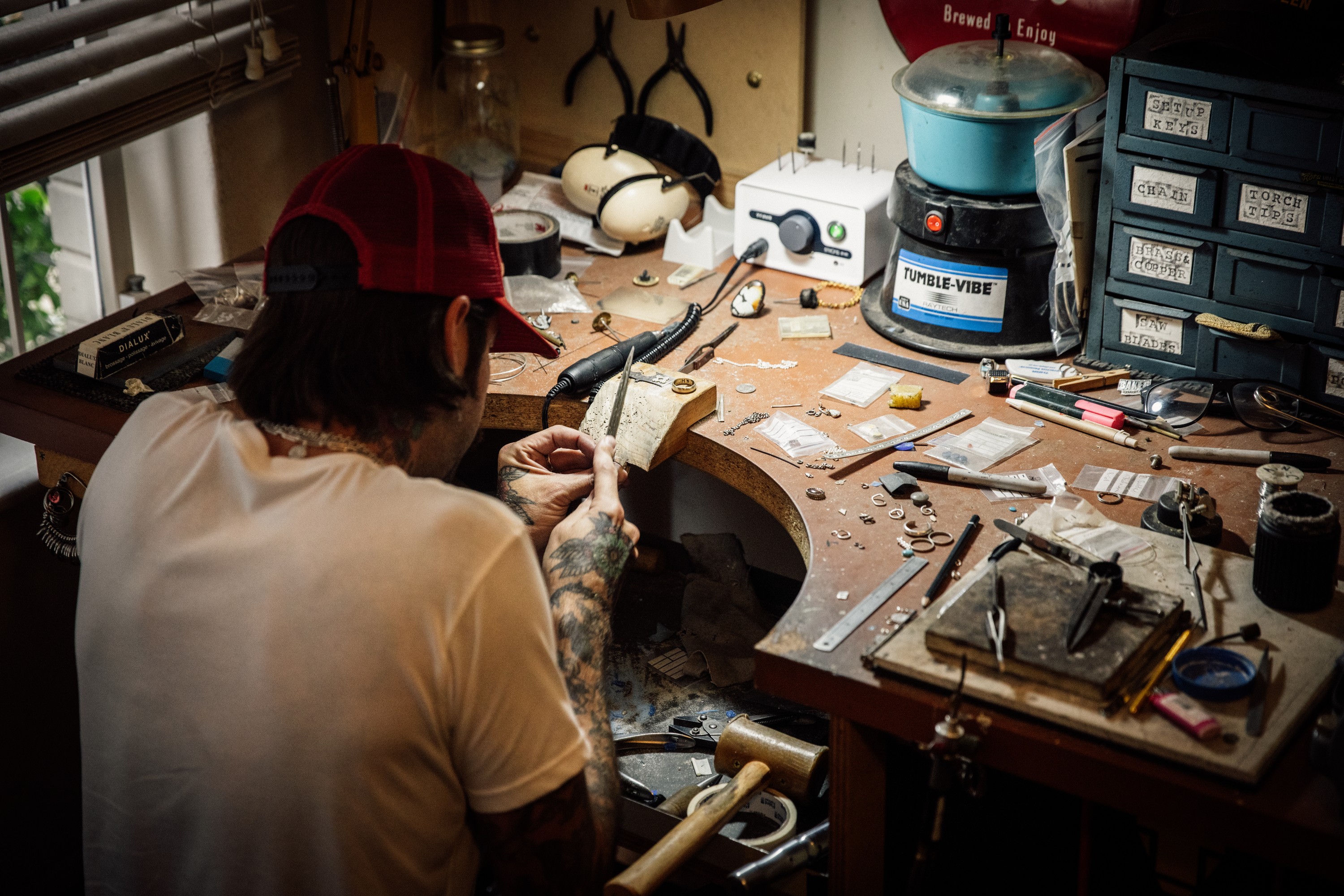 Adam working at his jeweller's bench in his home workshop, surrounded by tools